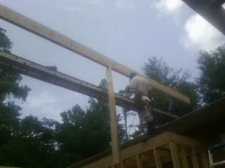 Carpenter setting a ridge beam over a new addition frame — Ice Dam Removal by Roofing Brothers in Healdton