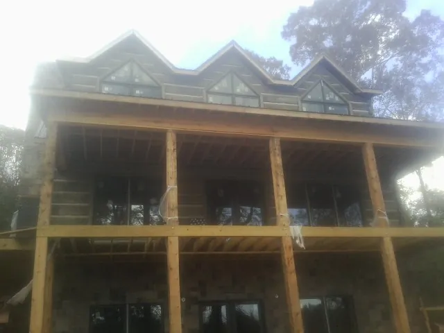 Dormers and porch framing on a large log home under construction — Roof Coating work by our crew in Healdton