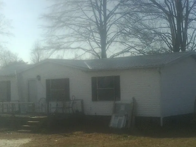 New metal roof on a white painted brick home on a foggy morning in Healdton