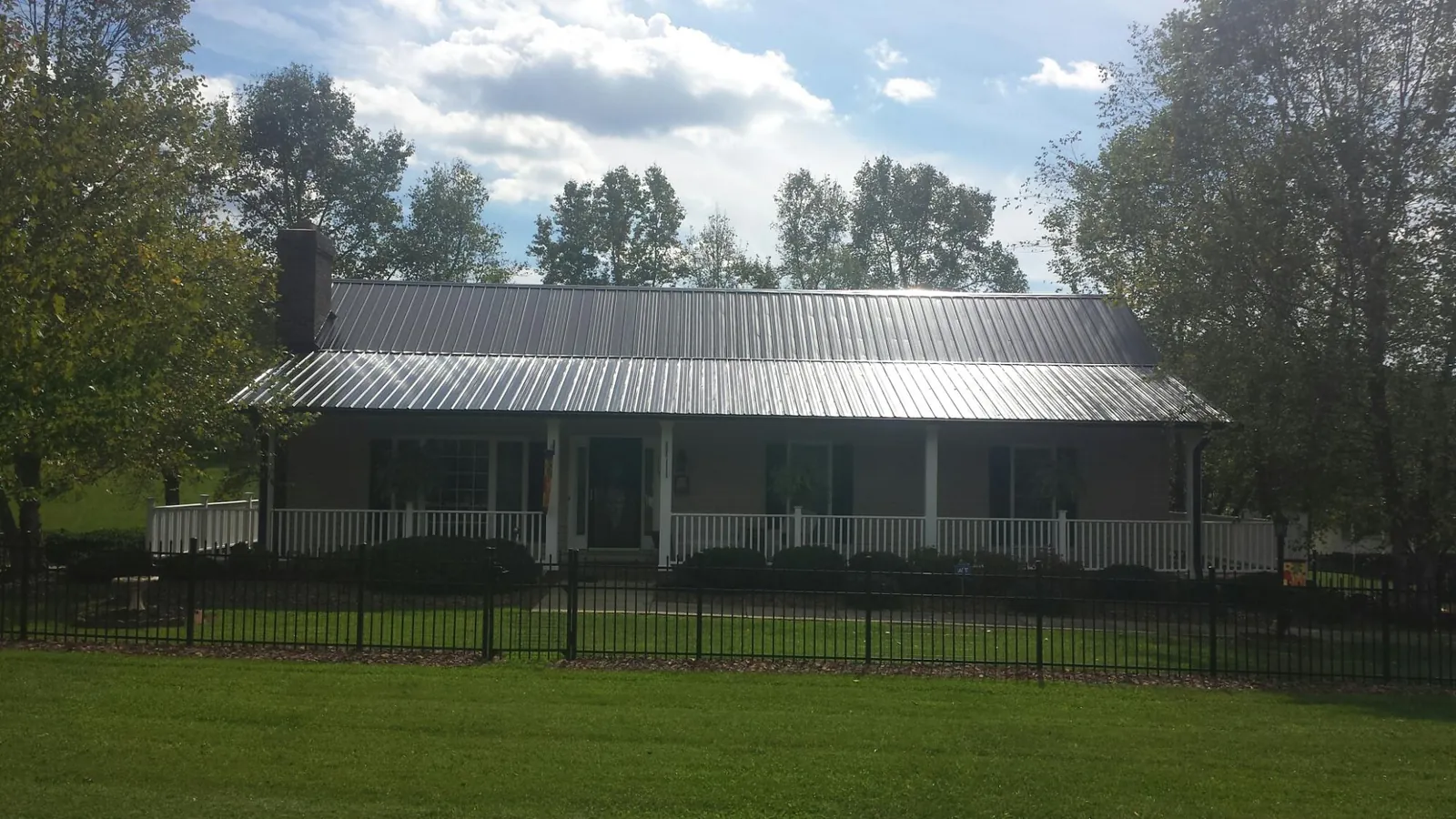 Gray metal roof on a brick ranch with a full width front porch — Gutter Guard Installation work by our crew in Healdton