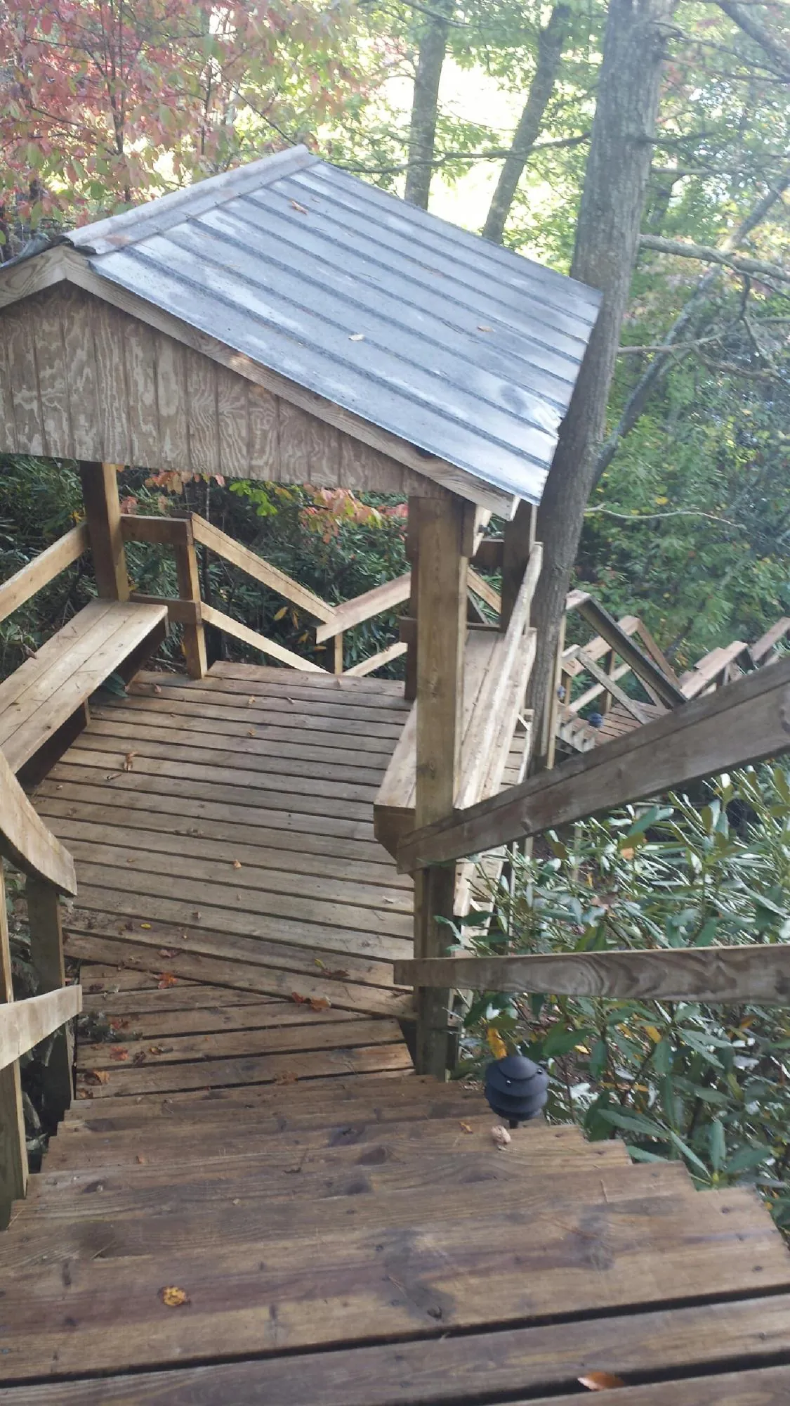 Metal roofed shelter over wooden steps on a wooded walkway — Skylight Repair & Installation work by our crew in Healdton