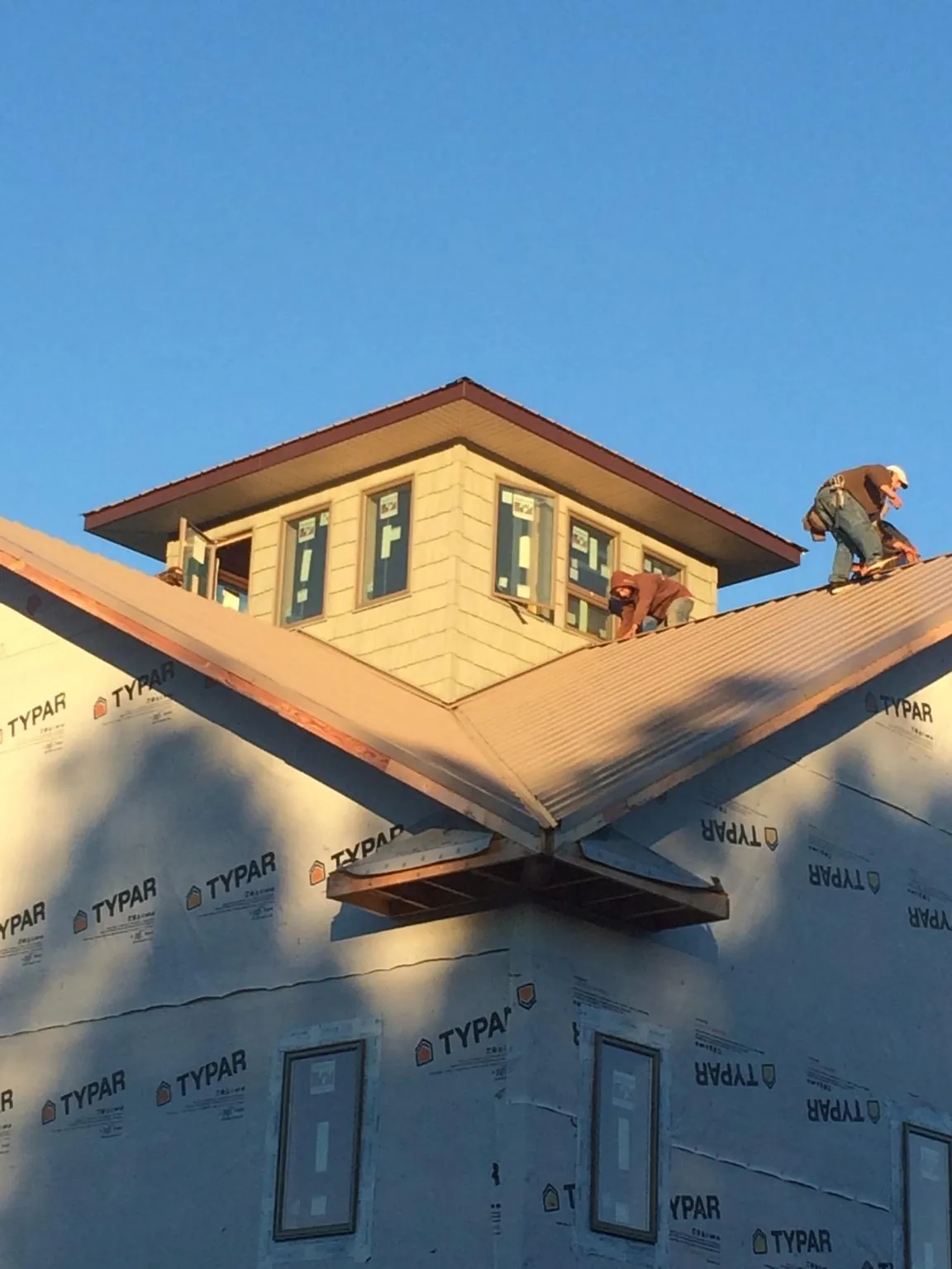 Roofers working around a rooftop cupola on a new metal roof at sunset — Roof Waterproofing in Healdton by Roofing Brothers